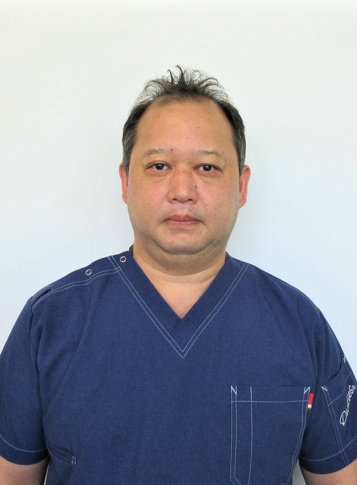 紺色スクラブを着用した男性職員のポートレート写真